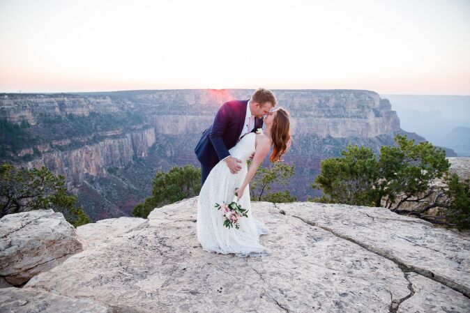A couple kisses for their wedding photo with a stunning view of the Grand Canyon.