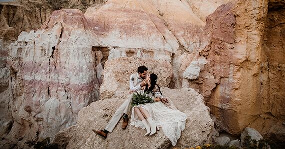 A couple posing after their wedding with beautiful rock wall background.